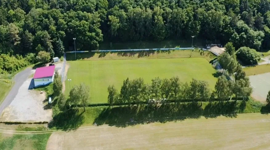 Luftaufnahme der gesamten Sportanlage zwischen Wald und Feldern