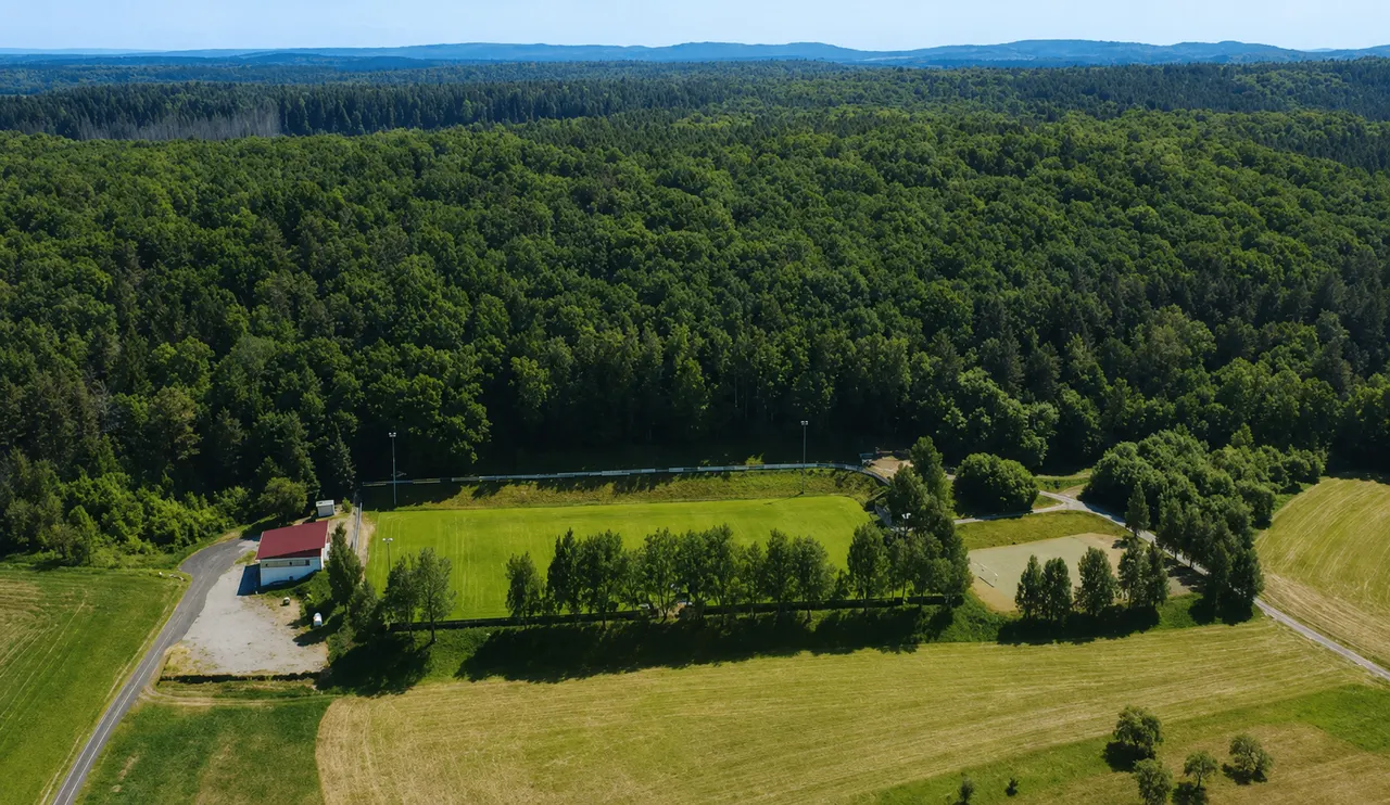 Luftbild des Sportplatzes „Am Pleckers“ zwischen Wald und Feldern