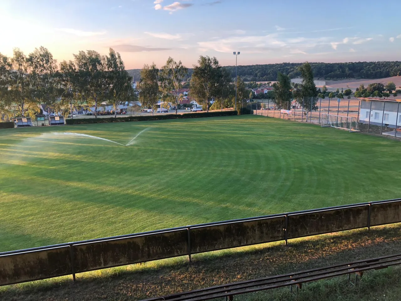 Der Rasenplatz „Am Pleckers“ am Abend mit Sprinkler und Blick auf Gellershausen